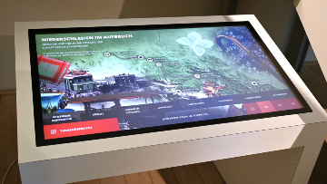 Ein interaktiver Touchscreen-Medientisch mit Animationen zeigt die Entwicklung von Gewerbe und Industrie entlang der Schlesischen Gebirgsbahn.
